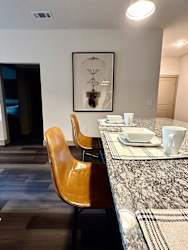 a dining area with a table and chairs and a picture on the wall