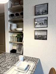 a corner of a kitchen with a counter and pictures on the wall