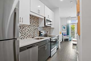 a kitchen with stainless steel appliances and white cabinets at Link Apartments® Mint Street, North Carolina