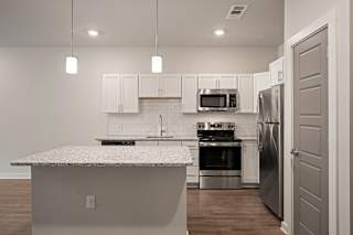 a kitchen with a marble counter top and stainless steel appliances at The Augustan, Augusta, GA