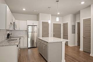 a kitchen with white cabinets and a stainless steel refrigerator at The Augustan, Augusta, GA