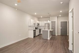 an open kitchen and living room with white cabinets and stainless steel appliances at The Augustan, Augusta, Georgia