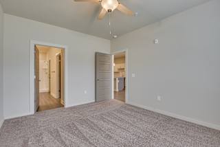 Spacious carpeted bedroom with ceiling fan and door to ensuite bathroom at The Augustan, Georgia, 30901