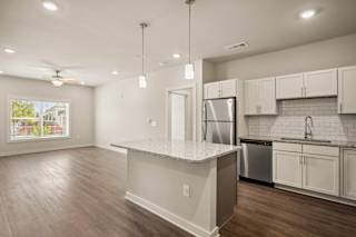 an open kitchen and living room with white cabinets and stainless steel appliances at The Augustan, Augusta