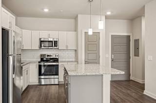 a kitchen with white cabinets and a marble counter top at The Augustan, Augusta, GA