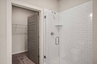 a white tiled shower in a bathroom with an open door at The Augustan, Augusta, 30901
