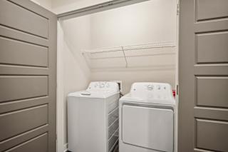 a white washer and dryer in a white laundry room with a door open at The Augustan, Georgia