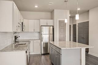a kitchen with white cabinets and granite counter tops and a stainless steel refrigerator at The Augustan, Georgia