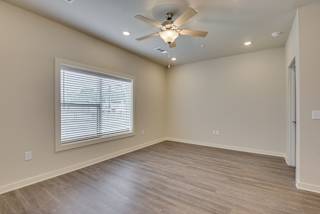 Living area with wood-like flooring, ceiling fan and large window at The Augustan, Augusta, 30901
