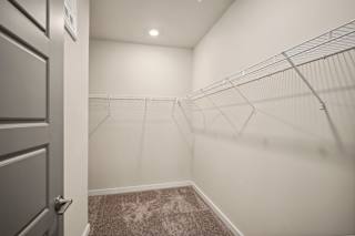 the walk in closet in a new home with white walls and a mirrored closet door at The Augustan, Augusta, GA