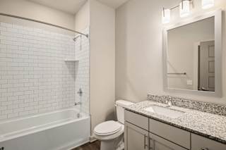 a bathroom with a shower toilet and sink and a mirror at The Augustan, Augusta, Georgia
