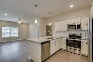 an empty kitchen with white cabinets and steel appliances at The Augustan, Georgia