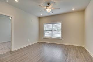 Living area with wood-like flooring, ceiling fan and window at The Augustan, Augusta, GA