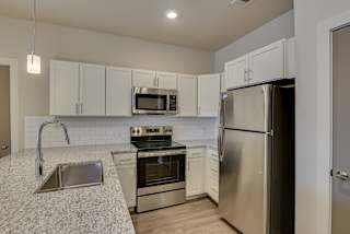 an empty kitchen with stainless steel appliances and granite counter tops at The Augustan, Georgia, 30901