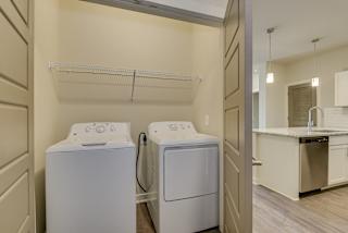 Washer and dryer in laundry closet with wire shelving at The Augustan, Augusta, GA