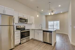 an empty kitchen with stainless steel appliances and white cabinets at The Augustan, Augusta, GA