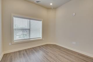 an empty room with wood floors and a large window at The Augustan, Augusta, 30901