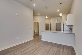 an open kitchen and living room with a large counter top and a white kitchen island at The Augustan, Augusta, GA