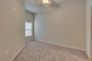 an empty bedroom with a ceiling fan and a window at The Augustan, Augusta, Georgia