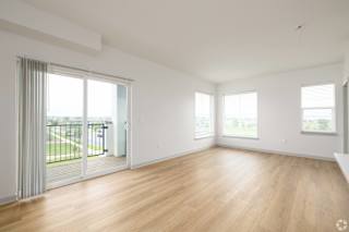 A spacious room with wooden floors and sliding glass doors. at Arbour Commons, Westminster, CO
