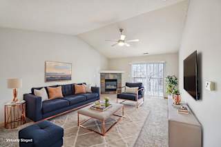 A living room with a blue couch and a television on the wall.
