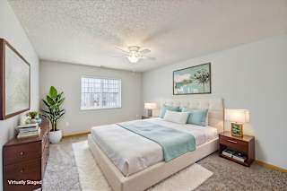 A bedroom with a bed, nightstand, and a plant.