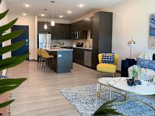 the view of the kitchen with dark cabinets from the corner of the living room