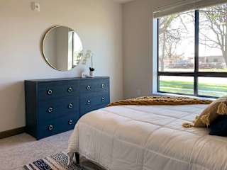 a bedroom with a bed and a blue dresser with a mirror