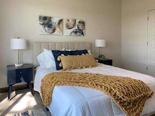 a bedroom with a bed, yellow and blue decorations, and nightstands on either side