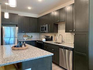 a kitchen with dark cabinets, stainless steel appliances, and granite counter tops