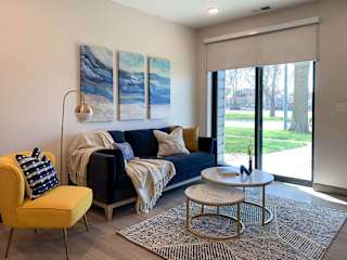 a living room with a blue couch, yellow chair, and a coffee table