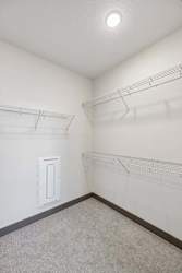 Spacious apartment walk-in closet with carpeted flooring, wraparound wire shelving, hanging space, and overhead lighting.