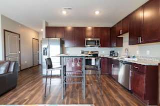 A kitchen with dark wood cabinets and light granite counters