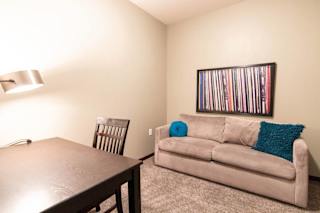 A room with a couch, chair, and a picture on the wall.