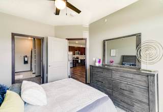 A bedroom with a bed, dresser, mirror, and a ceiling fan.