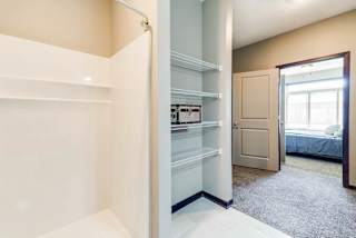 A white pantry with a door leading to a bedroom.