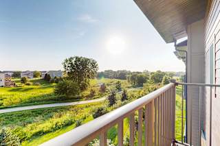A balcony overlooks a green landscape with houses in the distance.
