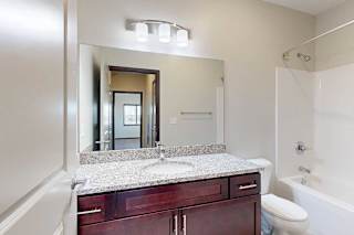 A bathroom with a granite countertop and a large mirror.