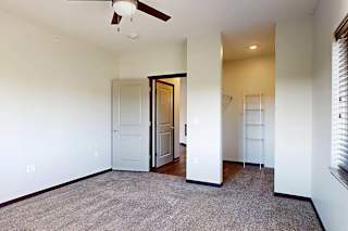 A bedroom with a ceiling fan, a large window, and a walk-in closet.