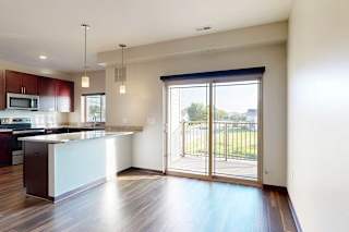 A dining area with a peninsula counter from the kitchen, and a large sliding glass door to a balcony.