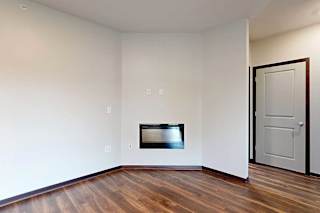 A living room with an electric fireplace and hardwood flooring.