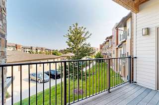 A balcony with a view of neighboring apartments and community green spaces.