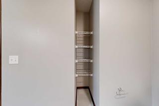 A bathroom with an inlet with built-in shelves for linen storage.