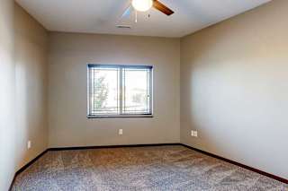 A carpeted bedroom with a large window and a ceiling fan.