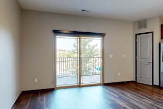 A living room with a sliding glass door to a balcony with a roller shade.