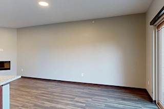 A living room with hardwood flooring, an electric fireplace, and a sliding glass door to a balcony.