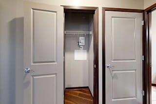 A hallway coat closet with a built-in wire shelf for hanging space.