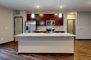 A modern kitchen with a large central island and pendant lighting.
