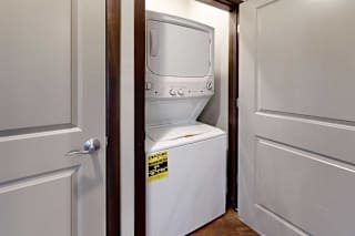 A stacked full-sized washer and dryer in a laundry closet.