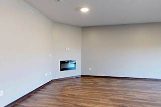 A living room with hardwood flooring and an electric fireplace.